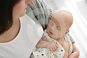 Mother holding her sleeping baby indoors, above view