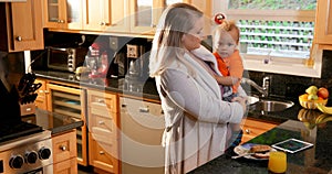 Mother holding her son in kitchen 4k