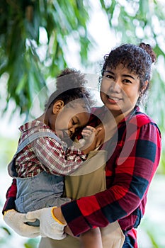 Mother holding his Daughter in her arms looking at her with love in vegetable garden. Happy loving mother holding daughter and lau