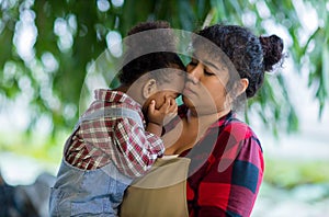 Mother holding his Daughter in her arms looking at her with love in vegetable garden. Happy loving mother holding daughter and lau