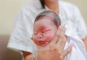 Mother holding infant baby head in her hands for belch after feeding photo