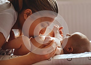 Mother holding and kissing new-born at home