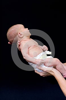 Mother holding newborn baby daughter against black background