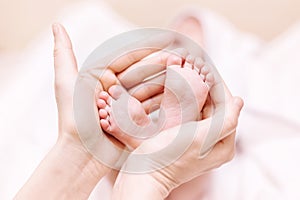 Mother holding newborn baby feet in hands. Mom taking care about infant child after taking bath. Parents childcare. Children