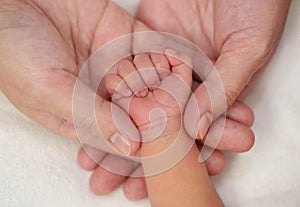 Mother holding newborn baby hand on bed