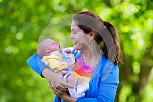Mother holding newborn baby in a park