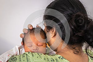 mother holding newborn baby at shoulder from flat angle