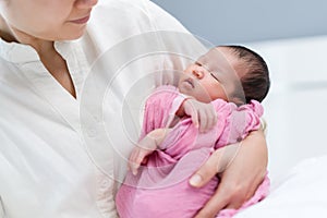 Mother holding newborn baby sleeping in arm