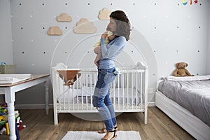 Mother Holding Newborn Baby Son In Nursery