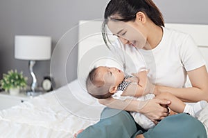 Mother holding newborn baby in a tender embrace on bed