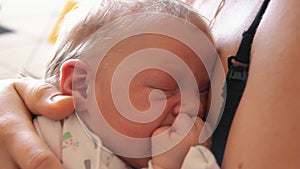 Mother Holding Newborn in Embrace and Breastfeed Her Infant, Close-up View of Baby Head, Tenderness and Care of Motherhood.