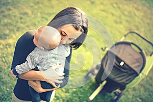 Mother holding newborn son in hands. Loving mother hand holding cute sleeping newborn baby child in park at sunset