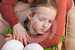 Mother holding sad teenager girl from behind - close up
