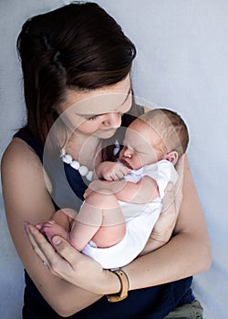 Mother holding sleeping newborn baby looking down