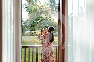 Mother holding a sleepy baby girl while standing