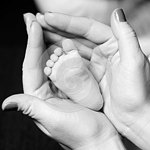 Mother holding tiny foot of newborn baby, close-up