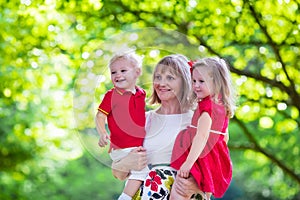 Mother holding two kids walking in summer park