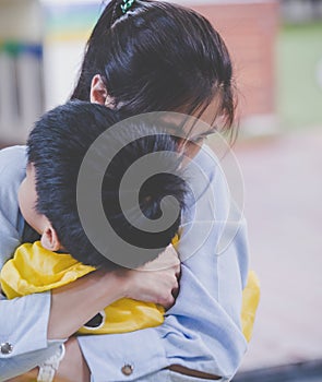 Mother holding an upset boy closely in her arm, for mother and parent caring concept