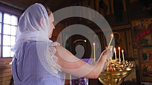 Mother holds the baby in her arms, prays and puts a candle in the church. Secret rite of baptism in the orthodox church