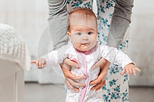 A mother holds the baby in her hands and teaches him to walk. Close up of baby portrait. Concept of teaching kids to walk