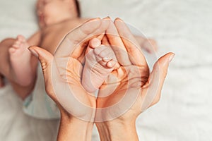 A mother holds the baby's foot in her palms. Hands close-up. Concept of motherhood and children's day