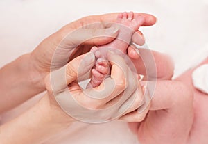 Mother holds the baby`s legs in her hands