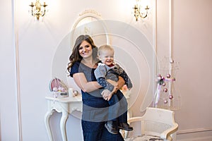 Mother holds child on hands near the mirror in the new year interior