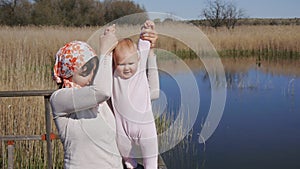 Mother holds hands of baby trying to walk