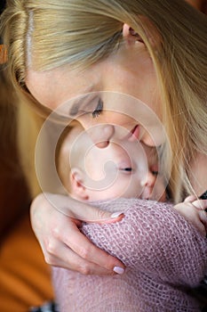 Mother holds on hands and gently presses to a breast of the newborn baby, motherhood