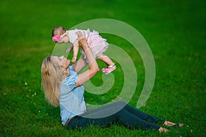 Mother holds on a hands her little baby on a grass