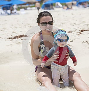 A mother holds her baby in the gentle ocean surf