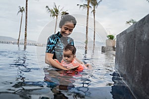 Mother holds her baby while learning to swim