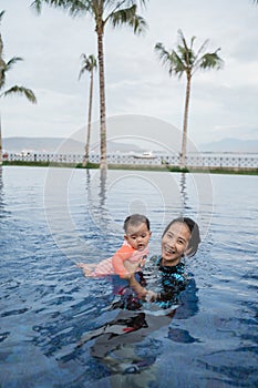 Mother holds her baby while learning to swim