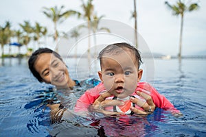 Mother holds her baby while learning to swim