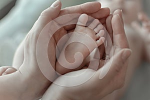 mother holds her baby's tiny foot in her hands