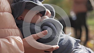 A mother holds a little baby in her arms during a walk