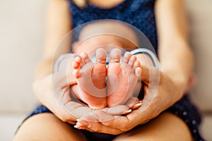 Mother holds little feet of newborn baby