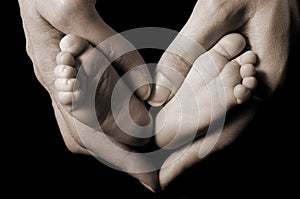 Mother holds newborn baby feet in a heart