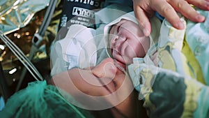 Mother Holds Newborn Baby in Hospital. Mother Holding Her Newborn Baby on Her Chest Just After Delivery. First Sight of