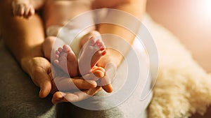 Mother holds newborn baby`s feets. Tiny feet in woman`s hand.