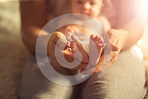 Mother holds newborn baby`s feets. Tiny feet in woman`s hand.