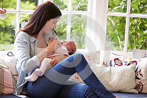 Mother At Home Cuddling Newborn Baby At Home