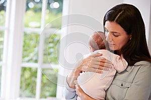 Mother At Home Cuddling Newborn Baby At Home