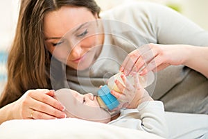 Mother at home feeding baby boy with a milk bottle
