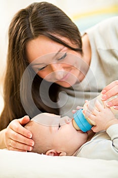 Mother at home feeding baby boy with a milk bottle