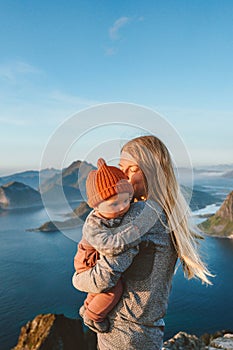 Mother hugging baby outdoor family traveling in Norway summer vacations mom with kid hiking in mountains