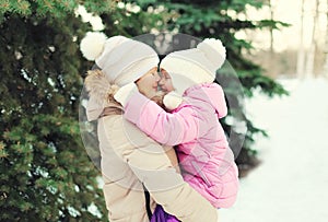 Mother hugging child near christmas tree in winter