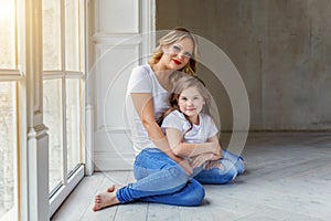 Mother and daughter hugging near windiow photo