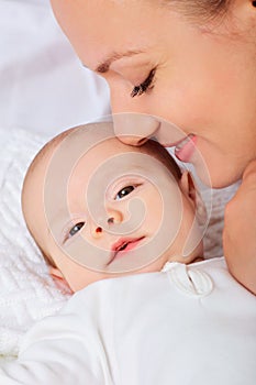 Mother hugging with her baby in the bedroom.Looking in the camera.