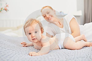 Mother hugging her baby lying on a bed